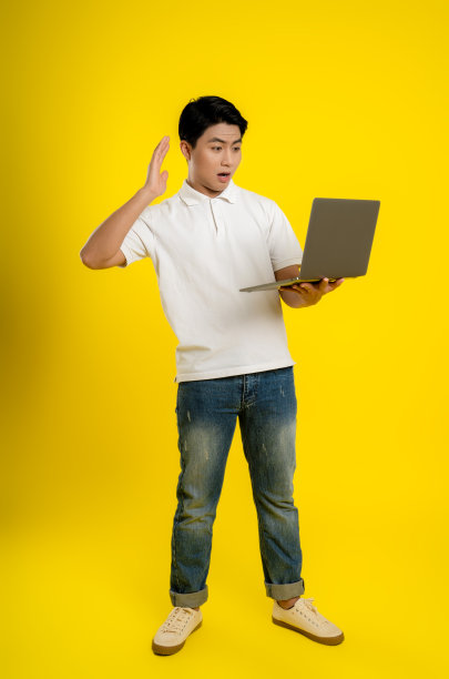 年轻的商人在黄色背景上使用笔记本电脑图片下载