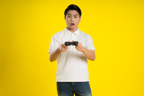 年轻的亚洲人在黄色背景上玩游戏的肖像图片下载