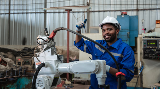 工业工程师在工业制造工厂中控制自动机械臂、焊接机、焊接机器人。图片下载