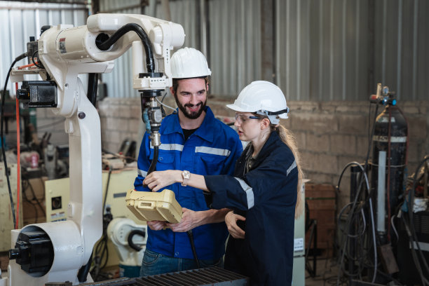 工业工程师在工业制造工厂中控制自动机械臂、焊接机、焊接机器人。图片下载