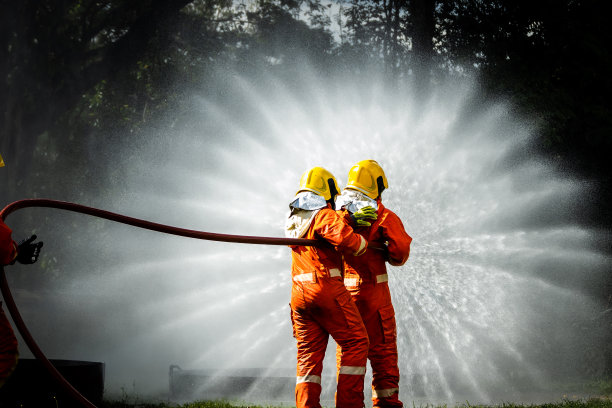 消防员的概念。消防队员用水和灭火器灭火。在一次消防训练演习中，消防员用水管和水扑灭火灾图片下载