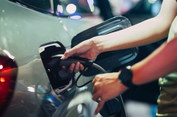 男子用电源插头给汽车充电特写图片下载