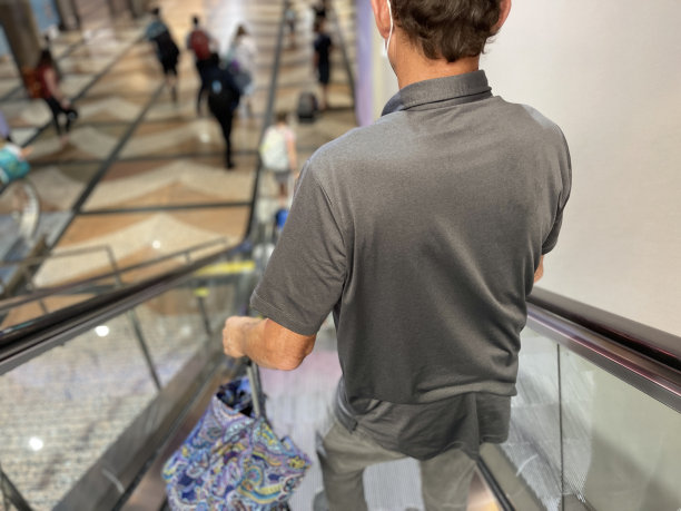 在2019冠状病毒大流行期间，丹佛国际机场自动扶梯上戴口罩的老人。后视图片下载