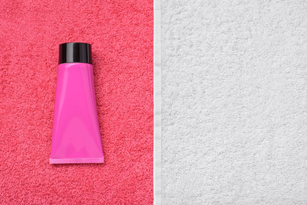 红白两色毛巾和装着面霜、沐浴露或牙膏的化妆管。图片下载