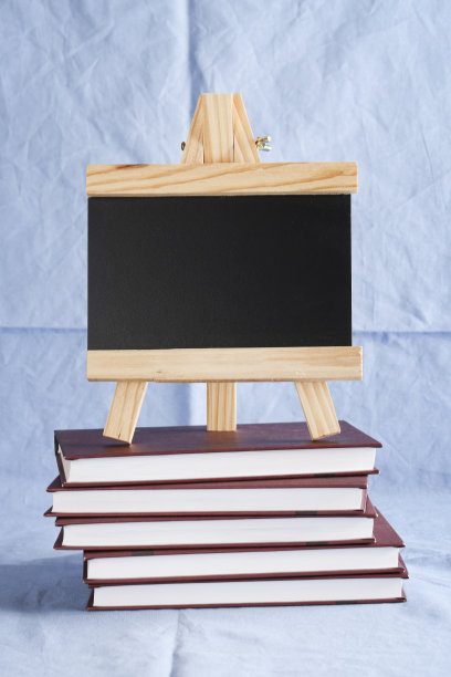 在蓝色纺织品背景上的一叠书上的黑色文字板。副本的空间。教育及展览、会议概念。回到学校图片下载