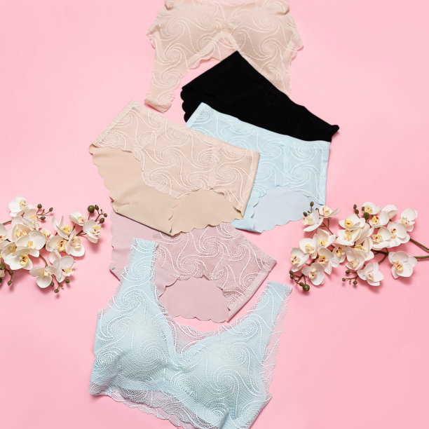一套彩色胸罩和内裤与白色兰花花在粉红色的背景图片下载