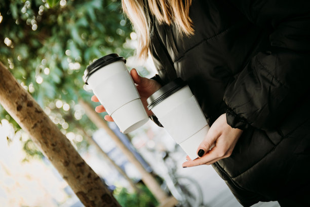 身着黑色连帽衫的年轻女子站在外面喝咖啡图片下载