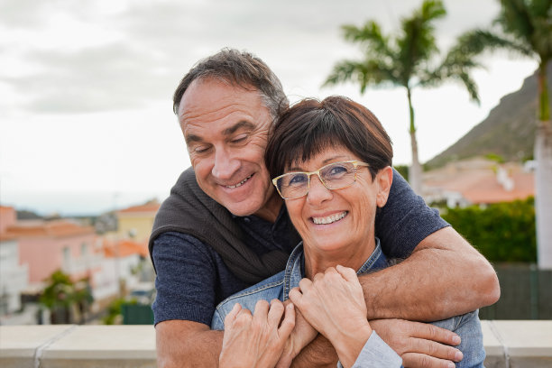幸福的老年夫妇在旅行度假期间在镜头前有温柔的时刻，背景是棕榈树图片下载