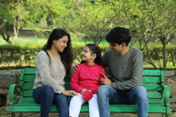 父母带着女儿在公园里享受着绿意和宁静。图片下载