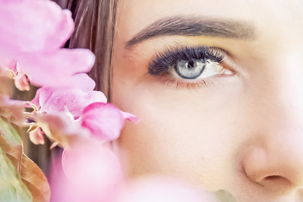 一个美丽浪漫的年轻女子的肖像，与一棵盛开的苹果树上的粉红色花朵的特写。化妆品，美容，时尚的理念。春天开花图片下载