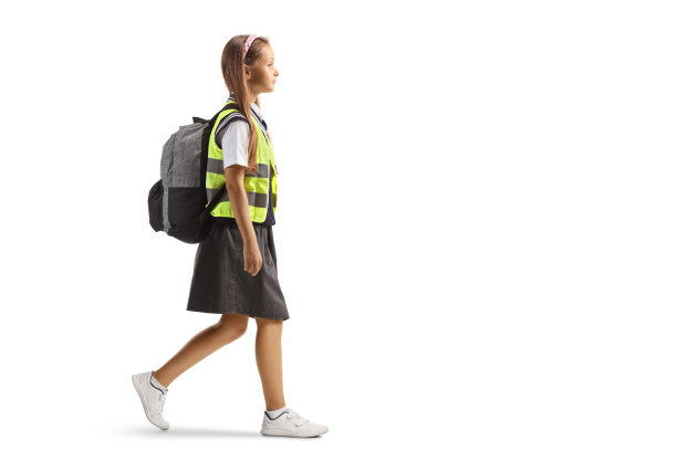 一个穿着反光背心走路的女学生的全身侧面照图片下载