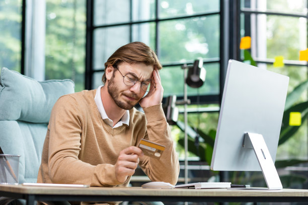 信用卡和银行账户有问题。上班族或自由职业者坐在办公桌前，厌倦了电脑，工作过度，头痛，需要休息和休息图片下载