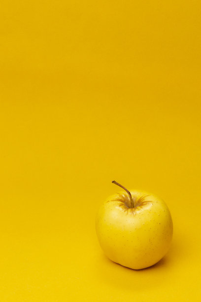 一个黄色的苹果果实在黄色的背景图片下载
