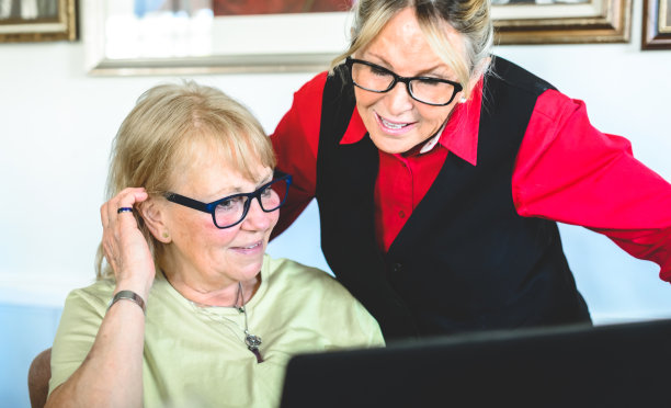 两个成年女性在室内使用笔记本电脑图片下载