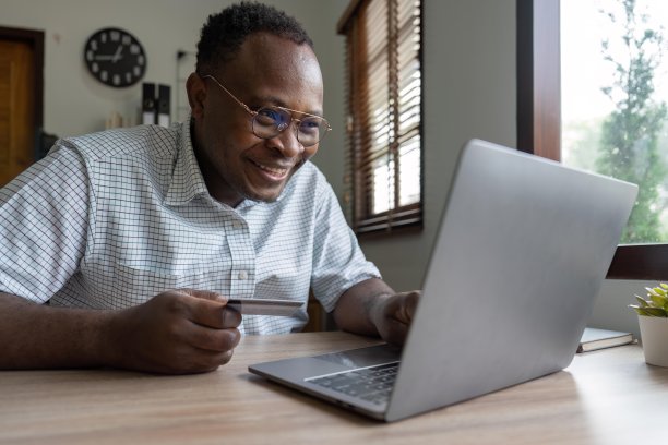 黑人男子手持信用卡进行网上购物和支付，在网上购物，网上支付，商业金融和科技图片下载