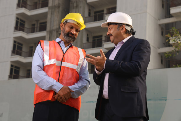 快乐的印度建筑经理与建筑工程师交谈。站在楼前讨论。图片下载