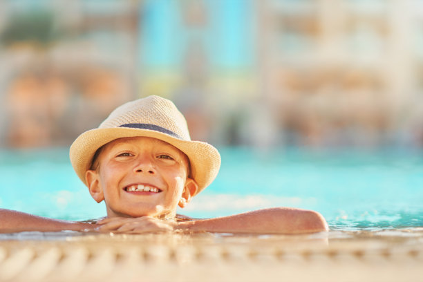 戴着帽子的小男孩在室外游泳池里玩耍的照片图片下载
