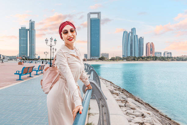 在阿布扎比繁忙的堤岸上，一位戴着鲜艳头巾的年轻女子格外引人注目，反映了她丰富的印度文化传统图片下载