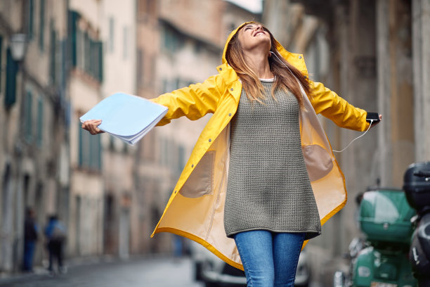 穿黄色雨衣的女人在散步时感到自由图片下载