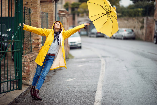年轻女性穿着雨衣，拿着伞站在户外图片下载