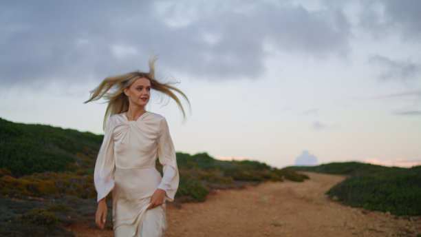 欢快的女孩跑上山特写。快乐的女人穿越日落的大自然图片下载