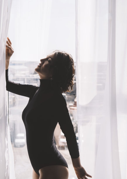 窗口前有个卷发的苗条女人。图片下载