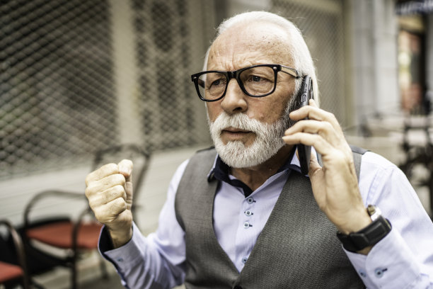 愤怒的老年商人在用智能手机通话图片下载