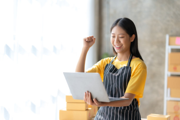 亚洲女性小企业主，对成功的笔记本电脑感到高兴。兴奋的成功。亚洲女商人举手示意。图片下载