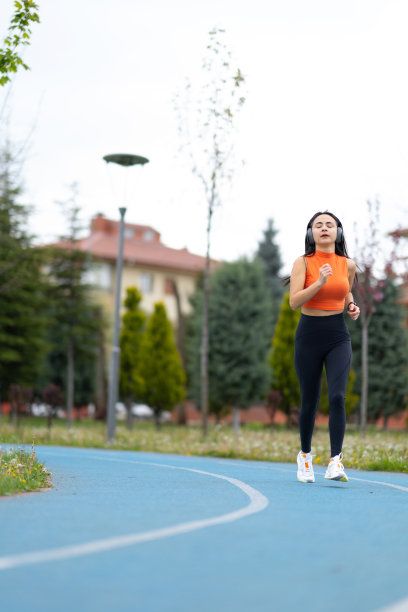 一个漂亮的女人正在跑道上跑步，戴着耳机听音乐图片下载