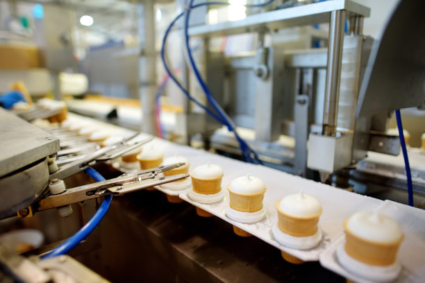 移动的传送带上准备打包的冰淇淋蛋筒的特写镜头。图片下载