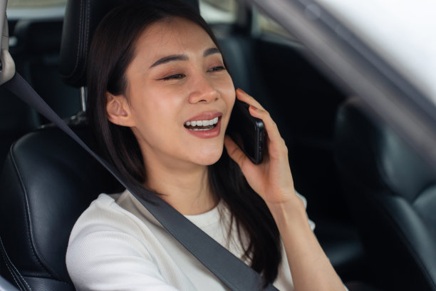 亚洲美女边开车边讲手机。迷人的年轻女孩在车里用智能手机和幸福聊天和交流。保护安全驾驶理念。图片下载