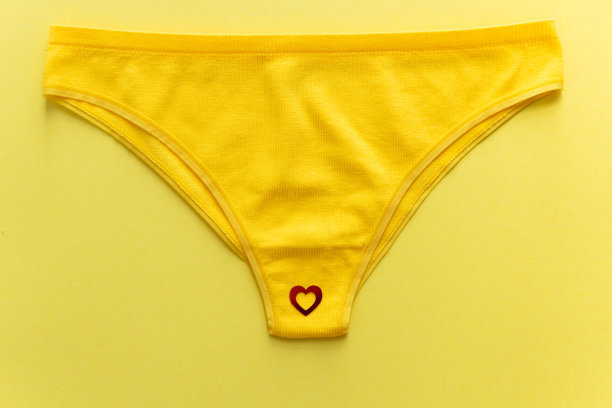 俯视图彩色女性内裤与红色的心形纸屑在黄色的背景，近距离。图片下载