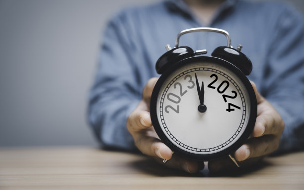 商人手持黑色闹钟，从2023年改为2024年，并有复制空间，准备“圣诞快乐”和“新年快乐”，开始商业变革和规划概念。图片下载