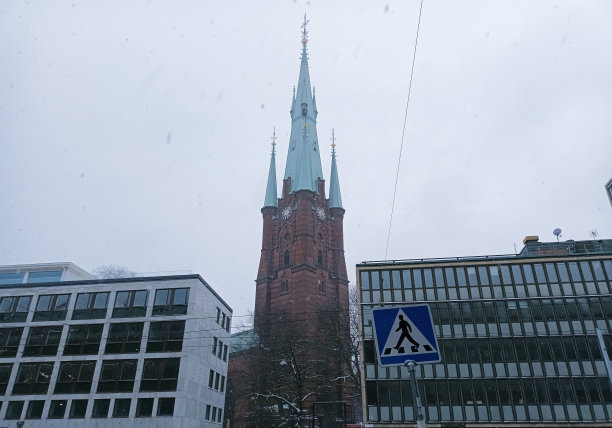 斯德哥尔摩，下雪天，圣克莱尔老教堂(Klara Kyrka)在现代建筑之间图片下载