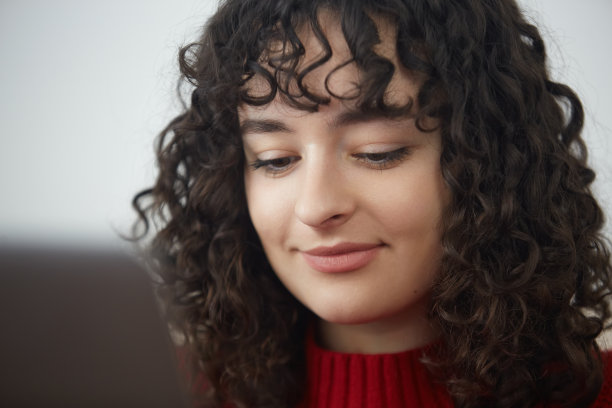 一个漂亮的黑发女孩在电脑前工作的画像。迷人的乌克兰女性，卷发，用笔记本电脑学习或工作图片下载