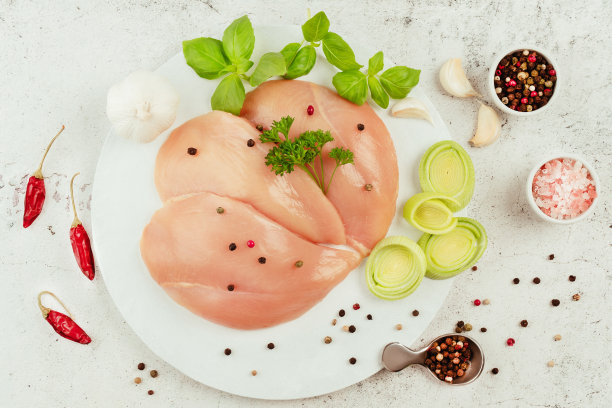 新鲜生鸡柳，灰色底色，配以新鲜香草。零售食品。设计师采购。有机食品，健康饮食。食品的概念。前视图。鸡胸片。关闭了。生鸡肉。图片下载