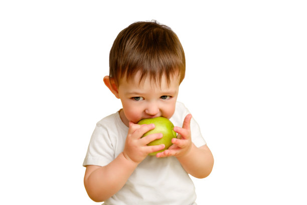 快乐的蹒跚学步的婴儿在白色背景的工作室里吃着一个绿苹果。孩子穿着白t恤，手里拿着一个大绿苹果，抄着空白处。一岁零四个月的孩子图片下载