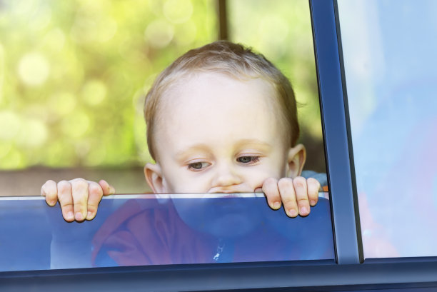 一个小男孩看着车外，眼里充满了悲伤。图片下载