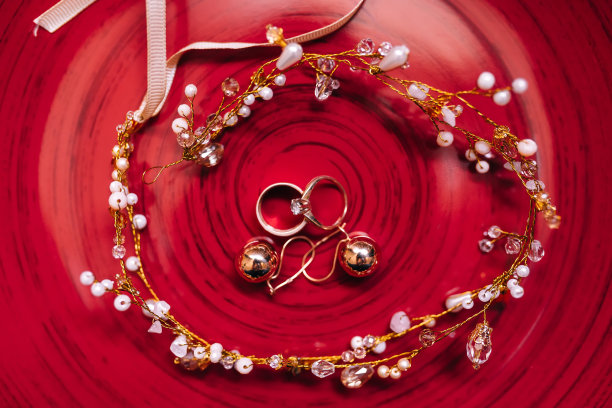 漂亮的结婚戒指和耳环放在新娘的红盘子上，是婚礼的配饰。图片下载