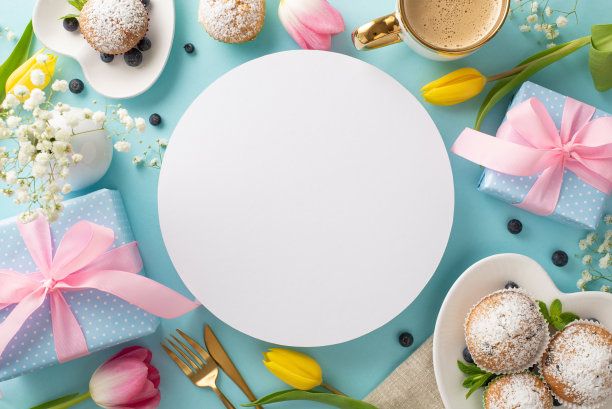母亲节概念快乐。顶视图平板上有美味的纸杯蛋糕，蓝色的礼物，一杯咖啡，淡蓝色背景上的郁金香。空圆圈显示文本图片下载