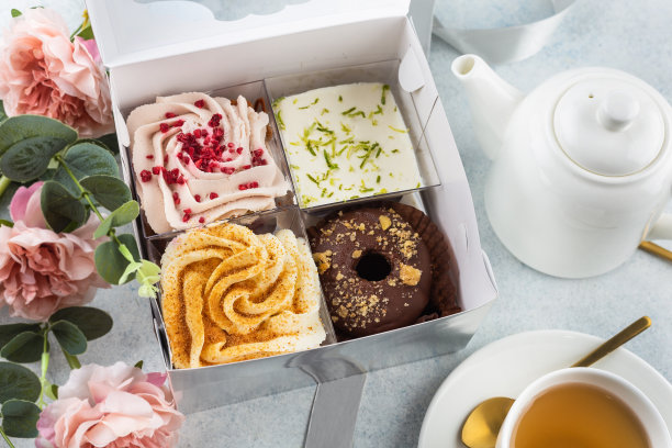一套装在白色盒子里的甜点(小蛋糕、棒棒糖蛋糕)和一杯茶。甜蜜的概念图片下载