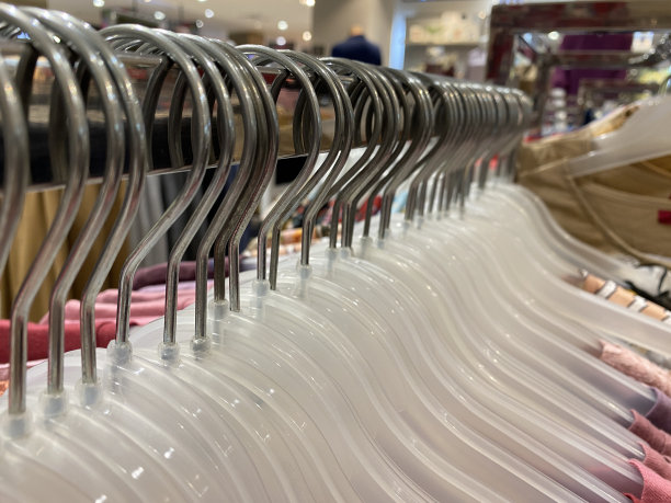 许多白色衣架挂在一根杆子上，孤立在购物中心的背景下。店铺概念、销售、设计、空衣架。放文字的地方。图片下载