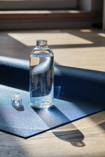 瑜伽垫上可重复使用的玻璃水瓶。图片下载