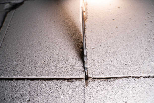 用手锯从加气混凝土块上切割墙壁的过程，在模糊的背景上进行加气混凝土特写。重建房屋，在墙上开个门图片下载