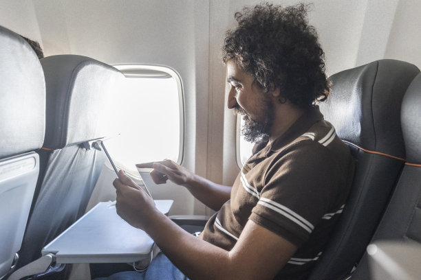 黑人在商业航班上使用平板电脑图片下载