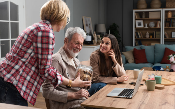 美丽幸福的家庭一起在桌子上，爸爸，妈妈，女儿，而爸爸在电脑上工作，女儿帮助他。老夫妇有孙女来访，他们给孙女饼干吃图片下载