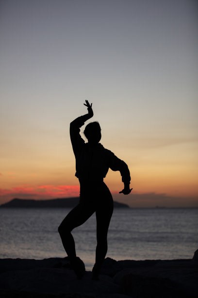 女人的剪影。她在日落时分跳舞。图片下载