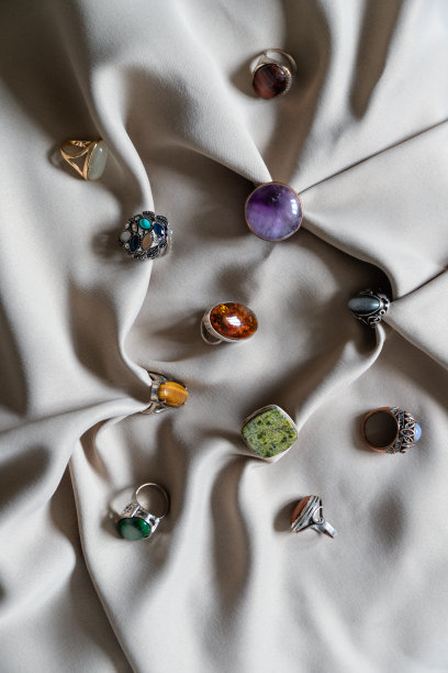 许多不同的银戒指与各种天然宝石在米色的背景。图片下载