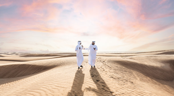 两个穿着阿拉伯坎杜拉的中东阿拉伯男子在沙漠中亲密接触图片下载
