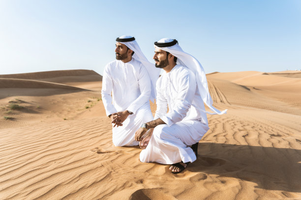 两个穿着阿拉伯坎杜拉的中东阿拉伯男子在沙漠中亲密接触图片下载